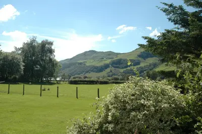 a field with a fence and mountains in the background at Dolffanog Fawr in Tal-y-llyn