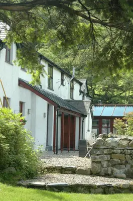 a white house with red doors and a stone wall at Dolffanog Fawr in Tal-y-llyn