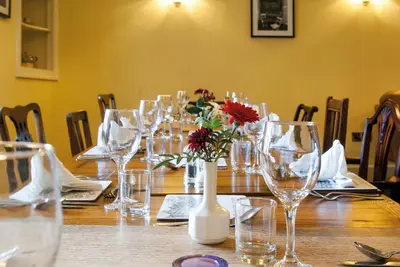 a long wooden table with glasses and a vase with flowers at The Dragon Hotel in Montgomery