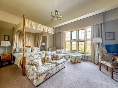 a bedroom with a canopy bed and a couch at Llangoed Hall in Bronllys
