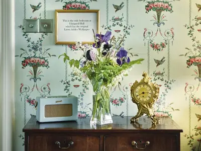 a vase of flowers sitting on a table with a clock at Llangoed Hall in Bronllys