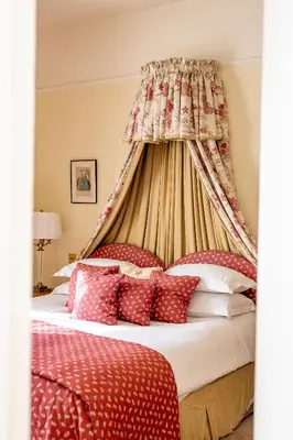 a bedroom with a canopy bed with red pillows at Llangoed Hall in Bronllys