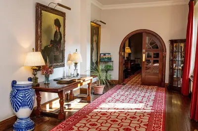 a room with a desk and a table with a rug at Llangoed Hall in Bronllys