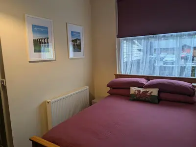 a bedroom with a bed with purple sheets and a window at Llangollen Hostel - Book Whole Room - Self Catering Facilities in Llangollen
