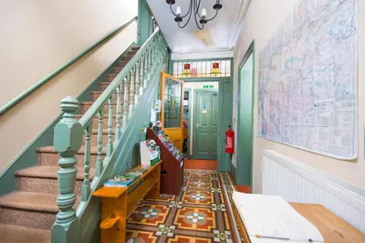 a hallway with a staircase with blue and green walls at Llangollen Hostel - Book Whole Room - Self Catering Facilities in Llangollen