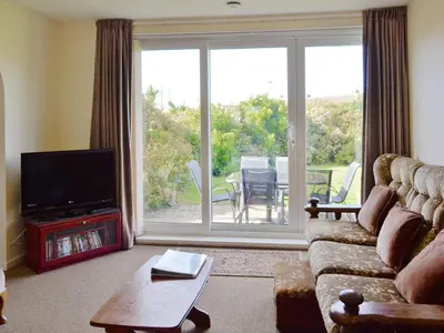 a living room with a couch and a sliding glass door at Fairlawns in Fairbourne