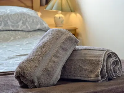 a towel laying on a bed next to a lamp at Fairlawns in Fairbourne