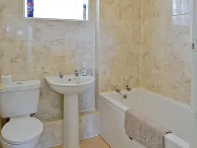 a bathroom with a toilet a sink and a bath tub at Fairlawns in Fairbourne