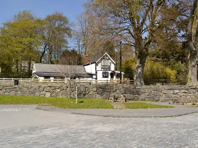 a white house with a stone wall and a stone fence at Y Bwthyn in Bala