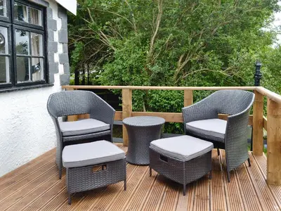 three wicker chairs and a table on a deck at Y Bwthyn in Bala