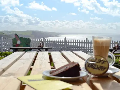 a table with a piece of cake and a cup of coffee at Cliff Railway Apartment in Aberystwyth