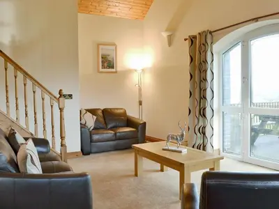 a living room with two chairs and a table at 5 Pengraig Draw in Llanychaiarn