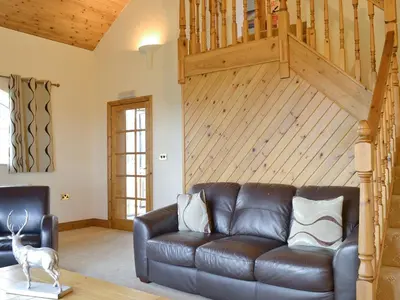 a leather couch in a living room with a wooden ceiling at 5 Pengraig Draw in Llanychaiarn