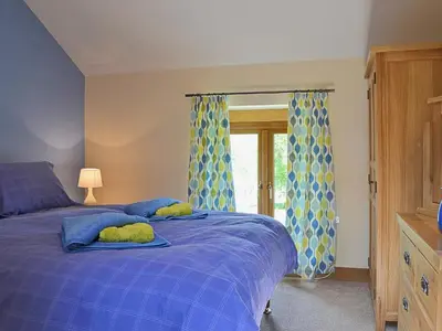 a bedroom with a blue bed with yellow pillows at Gorsddu in Llanwrthwl