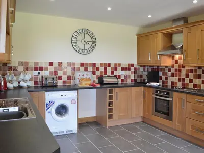 a kitchen with a washing machine and a clock on the wall at Gorsddu in Llanwrthwl