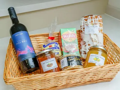 a basket filled with food and a bottle of wine at Cwmhyfryd in Llanllwchaiarn