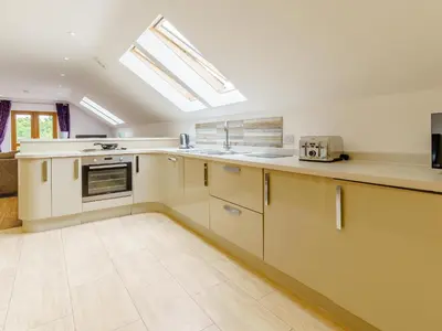 a large kitchen with white cabinets and a skylight at Cwmhyfryd in Llanllwchaiarn