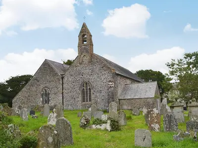 an old stone church with a clock tower in a graveyard at The Old Post Office in Myddfai