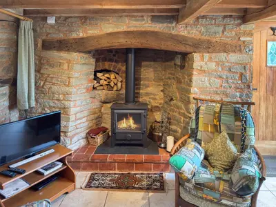 a stone fireplace in a living room with a couch and a tv at Acorn Cottage in Croft