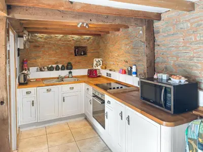 a kitchen with white cabinets and a microwave at Acorn Cottage in Croft