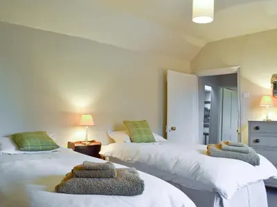 two beds with towels on them in a bedroom at Friary Cottage in Ludlow