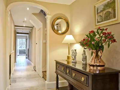 a hallway with a table with a vase of flowers on it at Friary Cottage in Ludlow