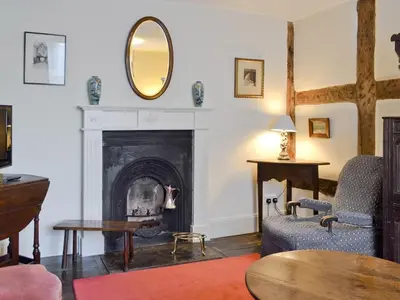 a living room with a fireplace and a mirror at Friary Cottage in Ludlow