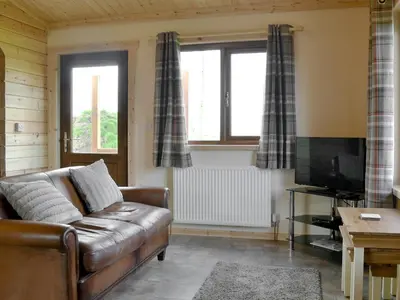 a living room with a brown leather couch and two windows at Callow Lodge in Meadowtown