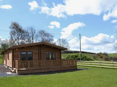 a log cabin with a porch and a fence at Callow Lodge in Meadowtown