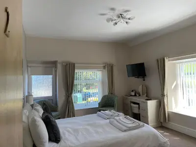 a bedroom with a white bed and two windows at Bwch yn Uchaf B&B in Llanuwchllyn