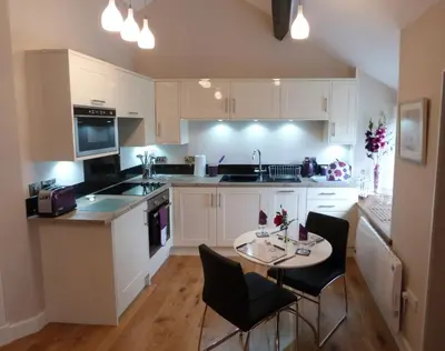 a kitchen with white cabinets and a table and chairs at Becws Clyd in Trawsfynydd