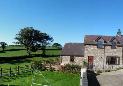 a stone house with a basketball hoop in front of it at Beudy Bach in Lampeter