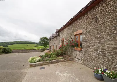a brick building with flowers on the side of it at Beudy Bach in Lampeter