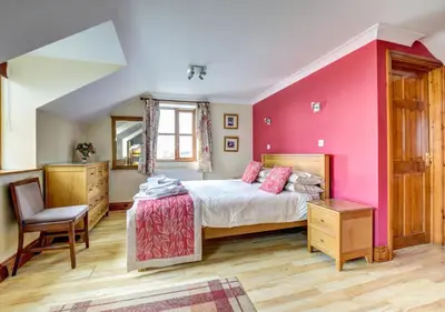 a bedroom with a bed and a pink wall at Beudy Bach in Lampeter