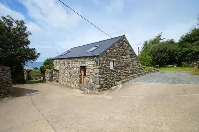 a stone building with a driveway in front of it at Beudy Taicroesion in Barmouth