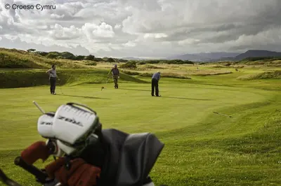 a group of people playing golf on a golf course at Beudy Taicroesion in Barmouth