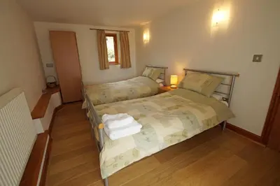 a bedroom with two beds and a window at Beudy Taicroesion in Barmouth
