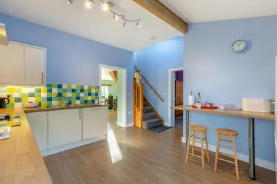a kitchen with blue walls and wooden floors and stools at 3 Bed in Aberystwyth oc-76692 in Llanilar