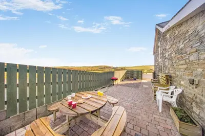 a wooden table and chairs on a brick patio at 3 Bed in Aberystwyth oc-76692 in Llanilar