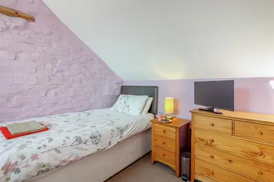 a bedroom with a bed and a dresser with a tv at 3 Bed in Aberystwyth oc-76692 in Llanilar