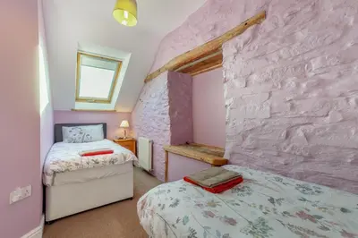 a bedroom with two beds and a stone wall at 3 Bed in Aberystwyth oc-76692 in Llanilar