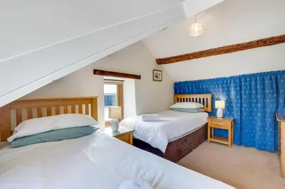 two beds in a attic bedroom with blue curtains at 2 Bed in Aberdyfi oc-78258 in Pennal