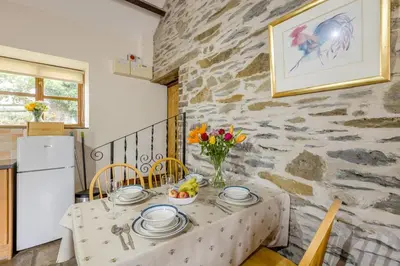 a dining room with a table and a stone wall at 2 Bed in Builth Wells oc-39471 in Builth Wells