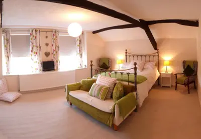 a bedroom with a bed and a couch and windows at Drws y Nant in Dolgellau