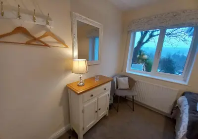 a bedroom with a desk with a lamp and a window at Gerddi'r Coed in Dolgellau