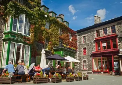 a group of people sitting at tables outside a building at Gerddi'r Coed in Dolgellau