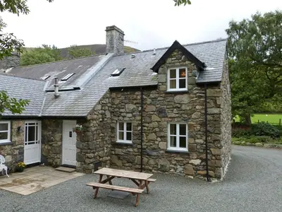 a stone house with a picnic table in front of it at Granar Gynolwyn in Abergynolwyn