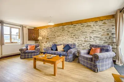 a living room with couches and a stone wall at 4 Bed in Builth Wells oc-39473 in Builth Wells