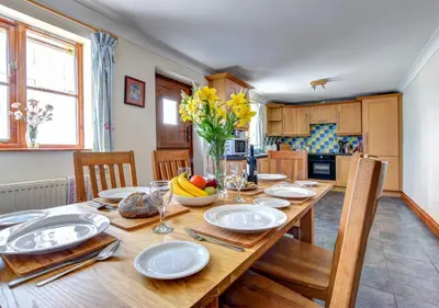 a kitchen with a wooden table with plates and fruit on it at Hen Ysgubor in Lampeter