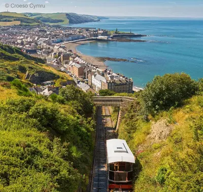 a train traveling down the tracks near the ocean at Llety'r Buarth in Talybont